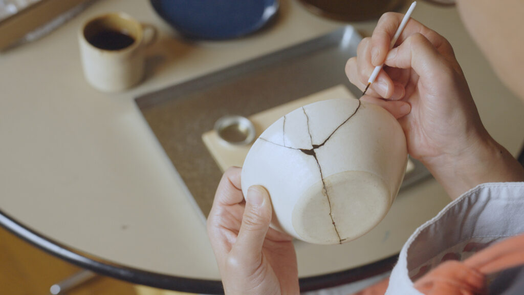 Woman repairing broken pottery. Kintsugi. Woman repairing broken pottery at home. Kintsugi.